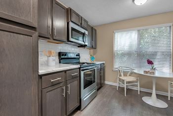 Kitchen with stainless steel appliances, granite countertops, and brown shaker cabinets.
